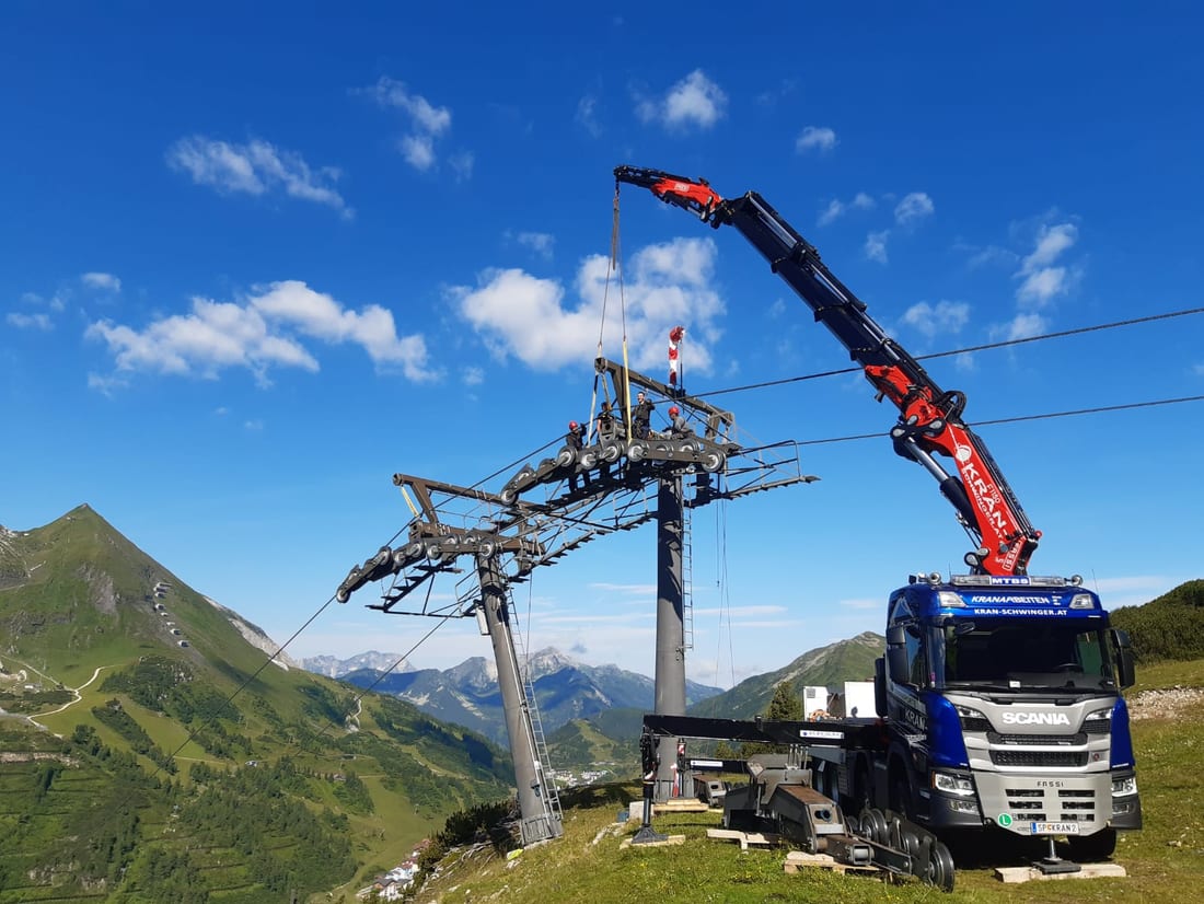 Kranmontage an der Stütze einer Seilbahn, Servicefahrzeug mit aufgestelltem Ladekran